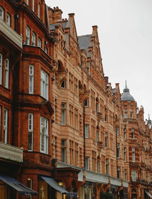 The image depicts a street view of Harrods department store in Knightsbridge, London, taken during the evening or late afternoon. The iconic building features ornate architecture with a prominent cent